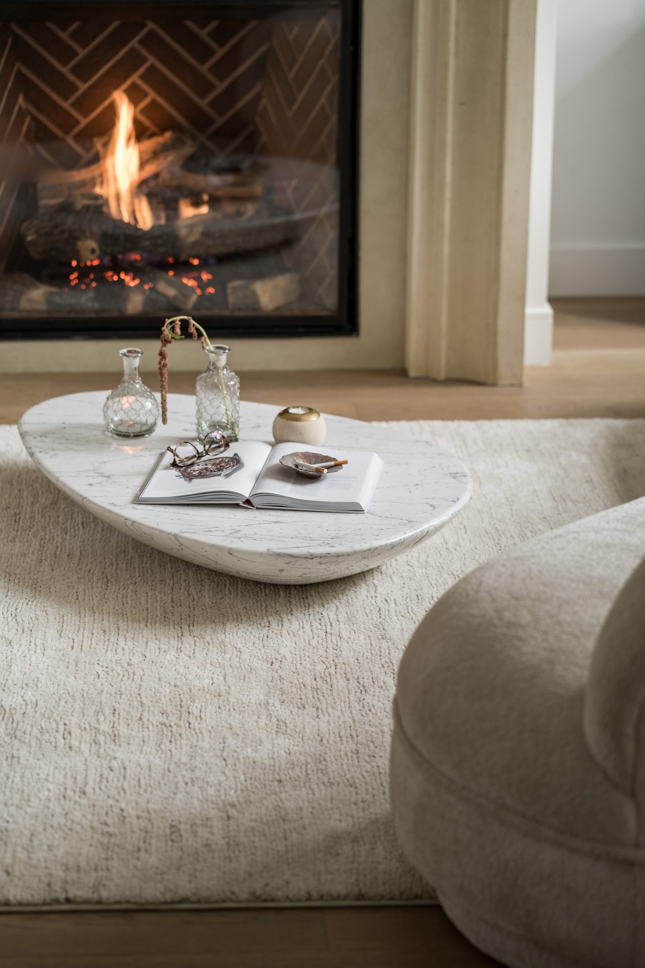 A lit fireplace and an organic-shaped stone coffee table in a warmly lit living room