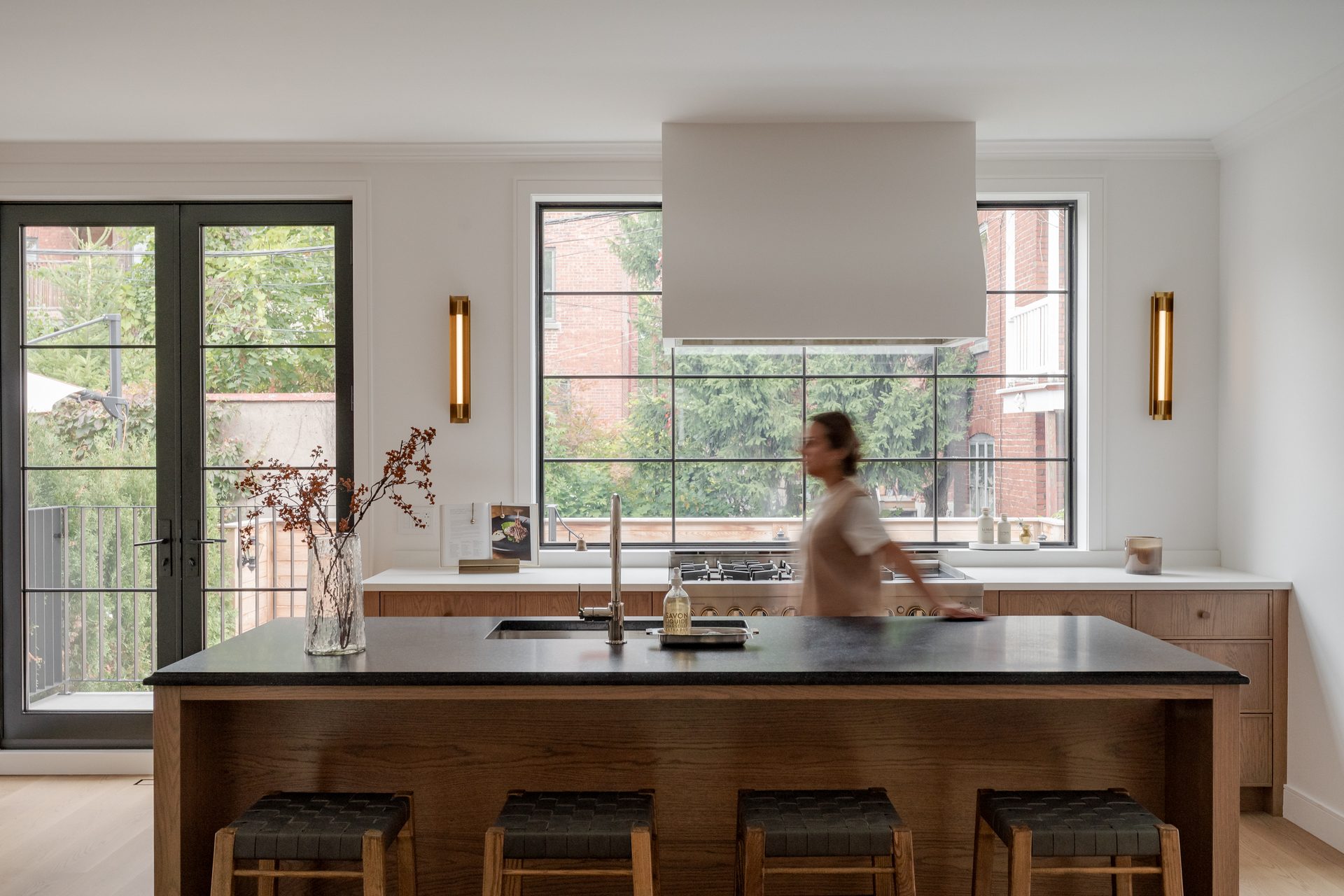 A sunlit modern Montreal residential interior with warm oak floors and travertine detailing